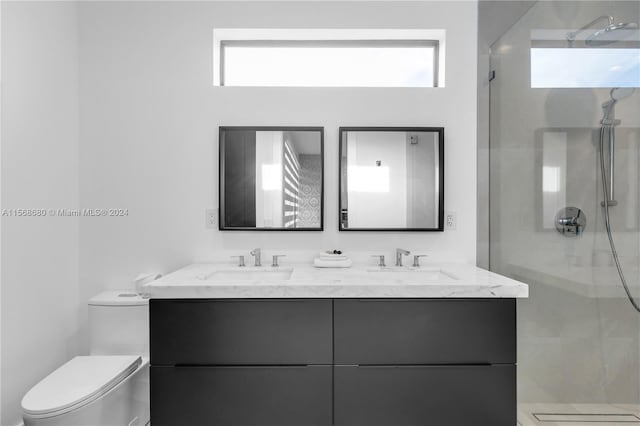 bathroom with dual vanity, a tile shower, and toilet