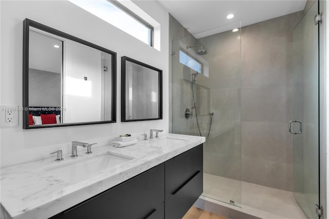 bathroom with wood-type flooring, a shower with door, and dual bowl vanity