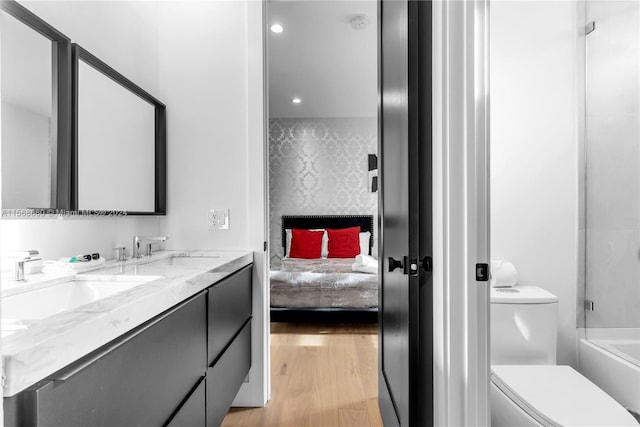 full bathroom with washtub / shower combination, wood-type flooring, toilet, and vanity