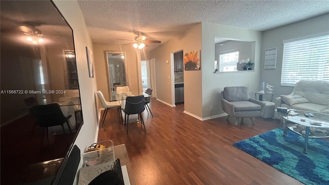 living room with dark hardwood / wood-style floors, ceiling fan, and a textured ceiling