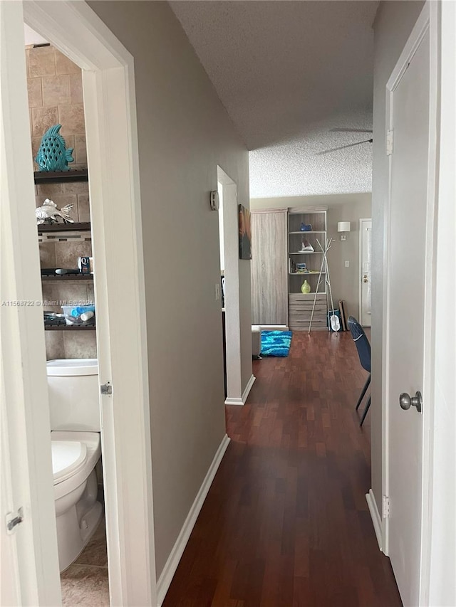 corridor featuring a textured ceiling and dark hardwood / wood-style flooring