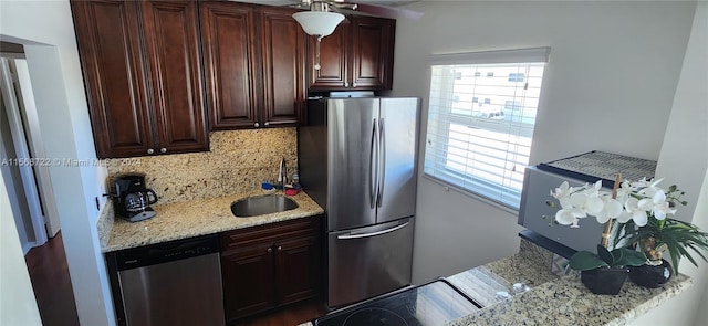 kitchen featuring dark brown cabinetry, light stone counters, appliances with stainless steel finishes, sink, and backsplash