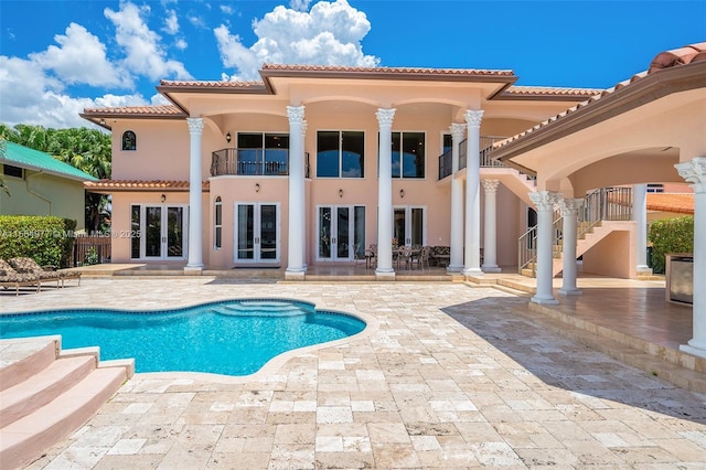 back of property with a fenced in pool, a patio area, french doors, and a balcony