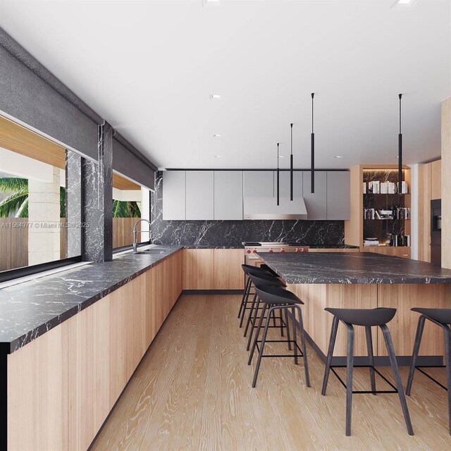 kitchen with a kitchen breakfast bar, light brown cabinets, light hardwood / wood-style flooring, and backsplash