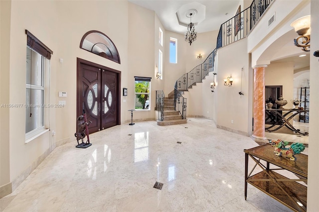 foyer entrance featuring a towering ceiling and decorative columns