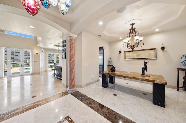 interior space featuring decorative columns, a chandelier, french doors, and a tray ceiling