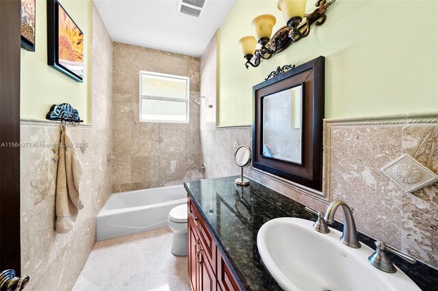 bathroom with vanity, toilet, tile walls, and a tub