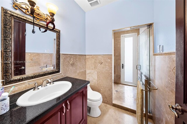 bathroom featuring vanity, toilet, and tile walls