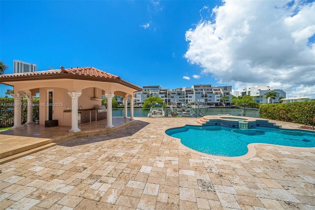 view of pool with an in ground hot tub, a patio, and a water view