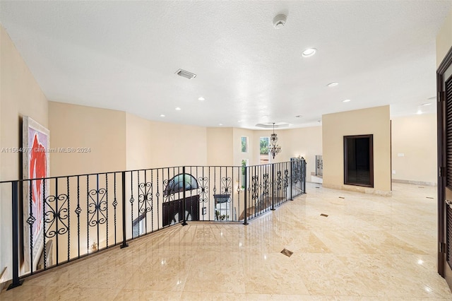 hall featuring a textured ceiling and an inviting chandelier