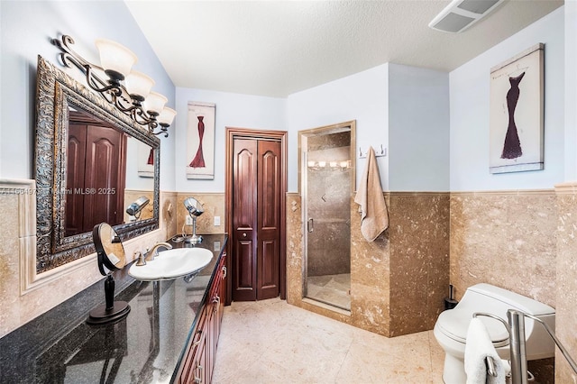 bathroom featuring tile walls, an enclosed shower, vanity, a textured ceiling, and toilet