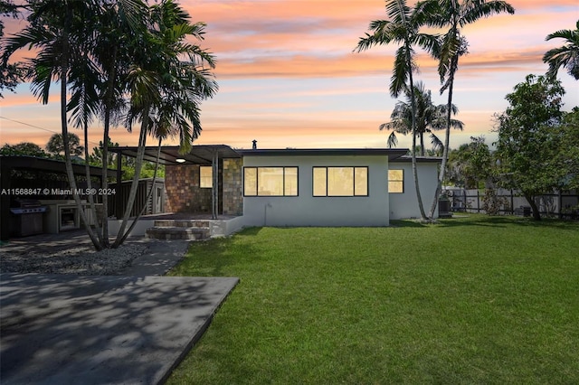 back house at dusk featuring a yard