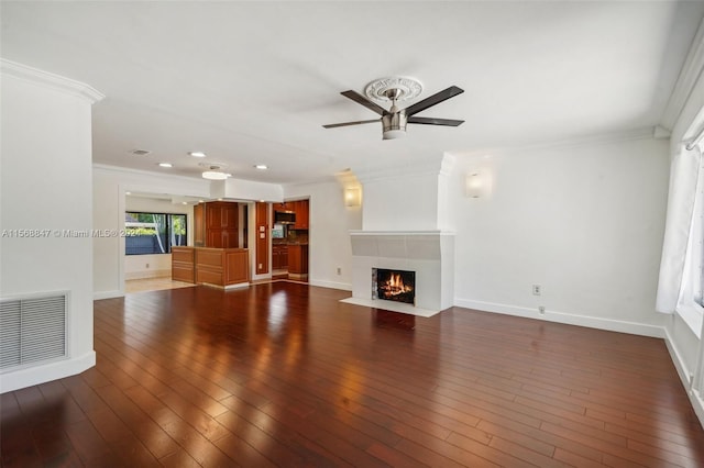 unfurnished living room featuring ceiling fan, dark hardwood / wood-style floors, crown molding, and a fireplace