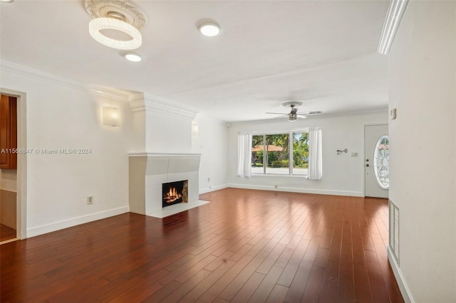 unfurnished living room featuring ceiling fan, wood-type flooring, crown molding, and a fireplace