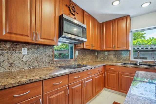 kitchen featuring a healthy amount of sunlight, backsplash, sink, and black electric stovetop