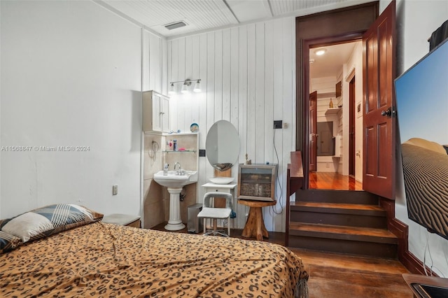 bedroom featuring sink and wood walls