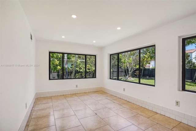 empty room with light tile patterned floors and plenty of natural light