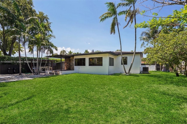 rear view of property with central air condition unit, a yard, and a patio