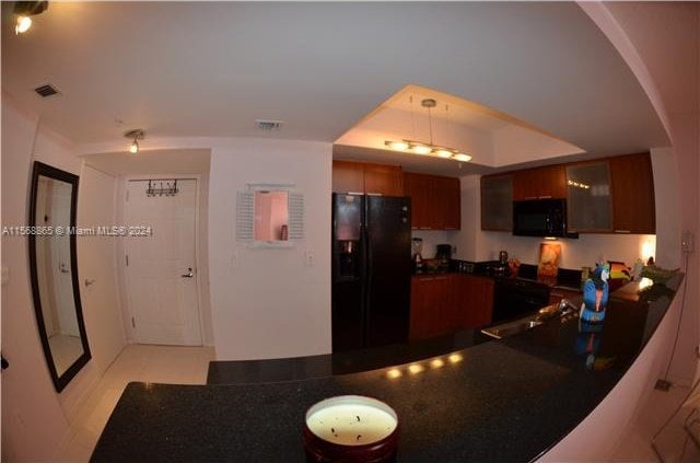 kitchen featuring kitchen peninsula, hanging light fixtures, black appliances, and light tile floors