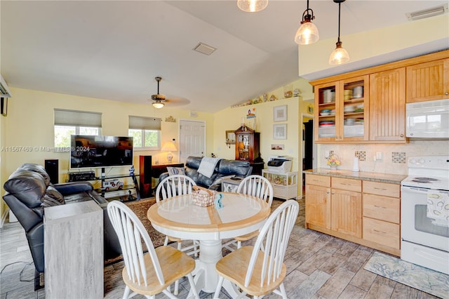 dining room featuring ceiling fan, light hardwood / wood-style flooring, and vaulted ceiling