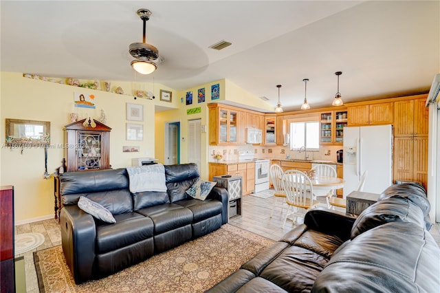 living room featuring ceiling fan, sink, lofted ceiling, and light tile patterned floors