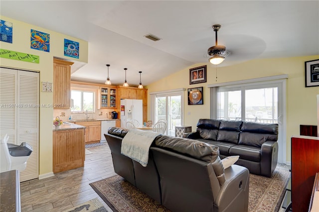 living room with light hardwood / wood-style flooring, vaulted ceiling, ceiling fan, and sink