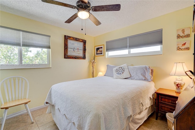 tiled bedroom featuring ceiling fan, a textured ceiling, and multiple windows