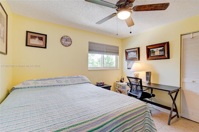 tiled bedroom with a textured ceiling, ceiling fan, and a closet