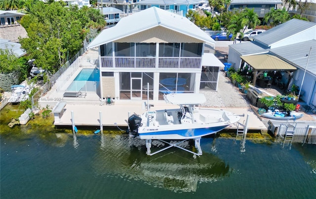 rear view of property featuring a patio, a sunroom, and a water view