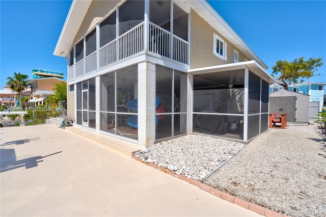 back of house with a patio, a sunroom, and a shed