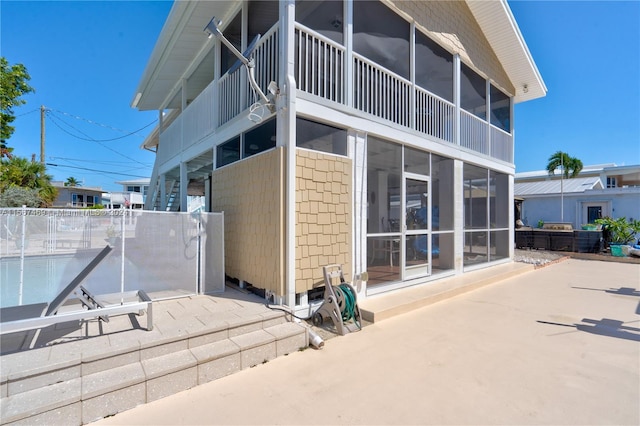 rear view of property featuring a balcony, a sunroom, and a patio area