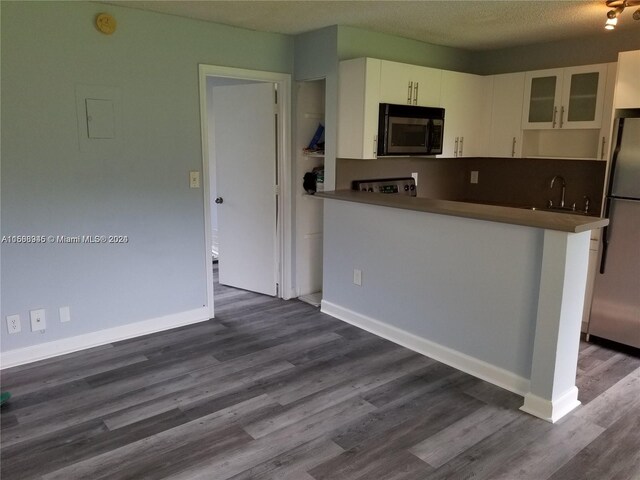 kitchen featuring stainless steel refrigerator, white cabinetry, dark hardwood / wood-style floors, kitchen peninsula, and a textured ceiling