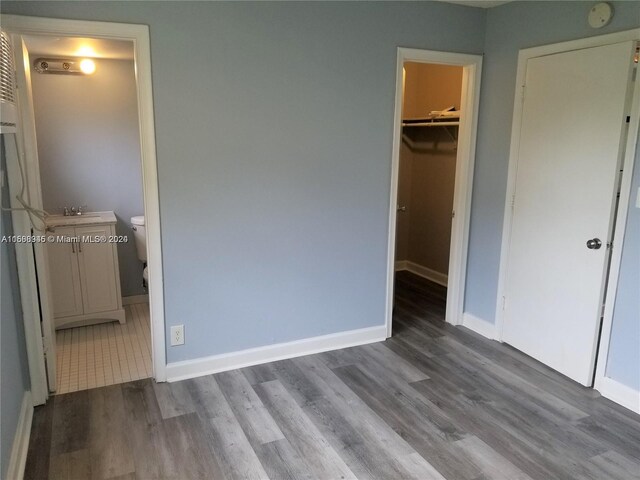 unfurnished bedroom featuring dark tile floors, connected bathroom, a closet, and a walk in closet