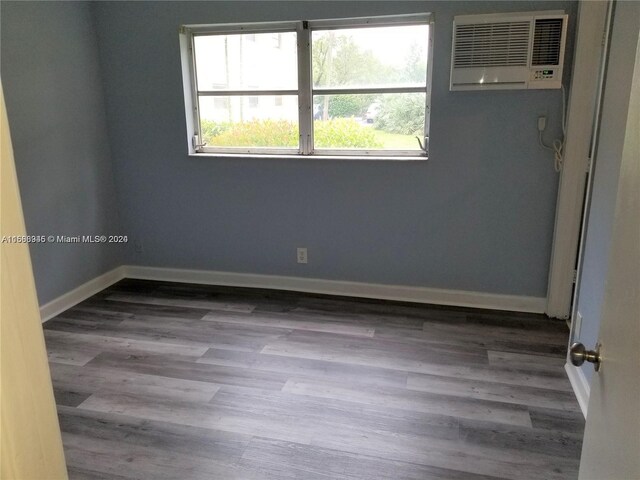 empty room featuring a wall mounted air conditioner and dark wood-type flooring