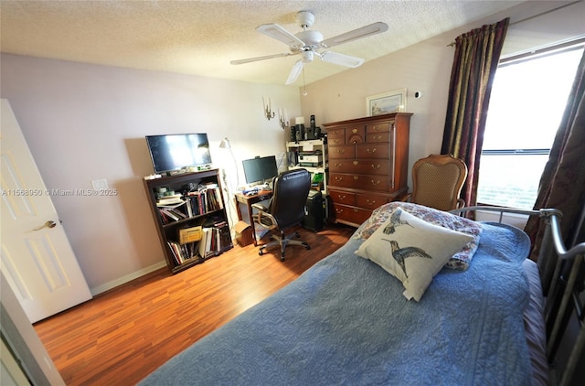 bedroom with a textured ceiling, ceiling fan, and hardwood / wood-style flooring