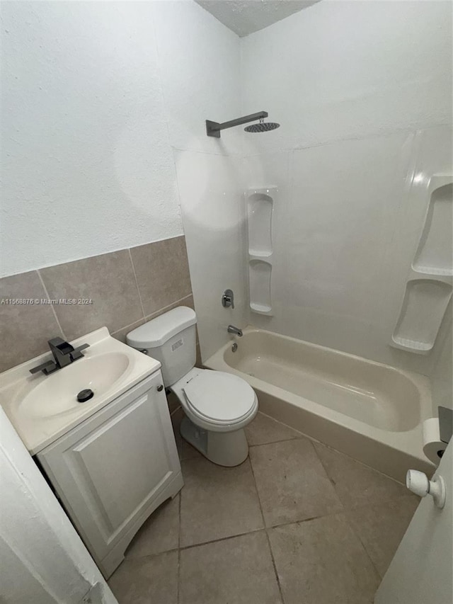 full bathroom with tile walls, bathing tub / shower combination, toilet, vanity, and tile floors