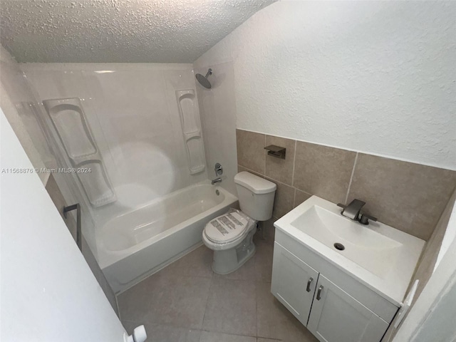 full bathroom with tile walls, toilet, a textured ceiling, vanity, and tile floors