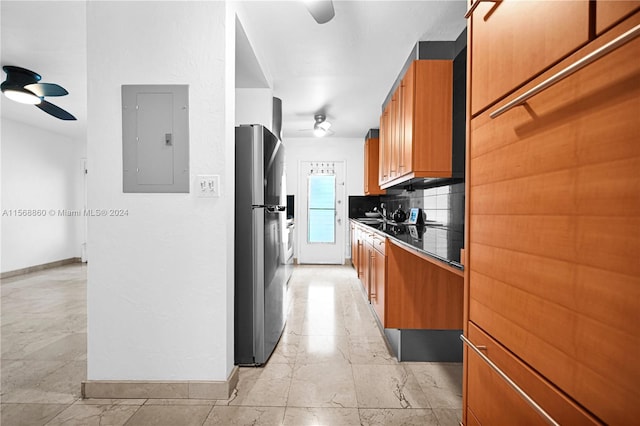 kitchen with stainless steel refrigerator, electric panel, ceiling fan, and tasteful backsplash