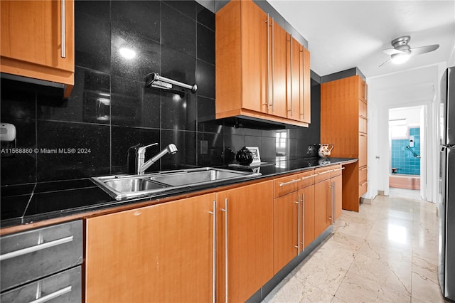 kitchen with decorative backsplash, ceiling fan, stainless steel refrigerator, and sink