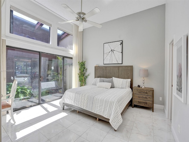 tiled bedroom with multiple windows, ceiling fan, access to exterior, and a high ceiling