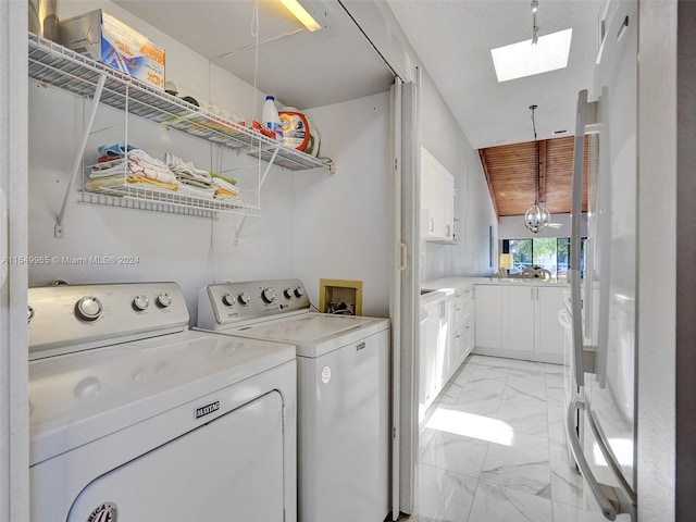 laundry area with a skylight, hookup for a washing machine, light tile flooring, and washer and dryer