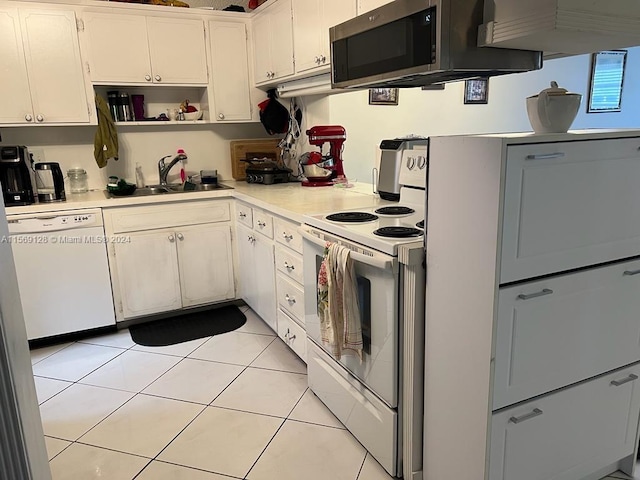 kitchen featuring white appliances, sink, light tile floors, and white cabinetry