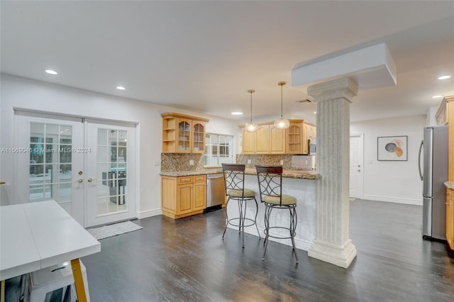 kitchen with a kitchen bar, light stone counters, ornate columns, backsplash, and dark wood-type flooring