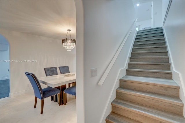 staircase with an inviting chandelier and light wood-type flooring