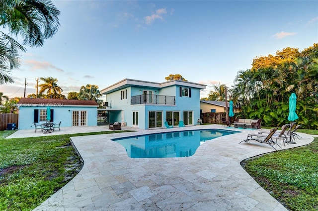 pool at dusk with french doors, a yard, and a patio area