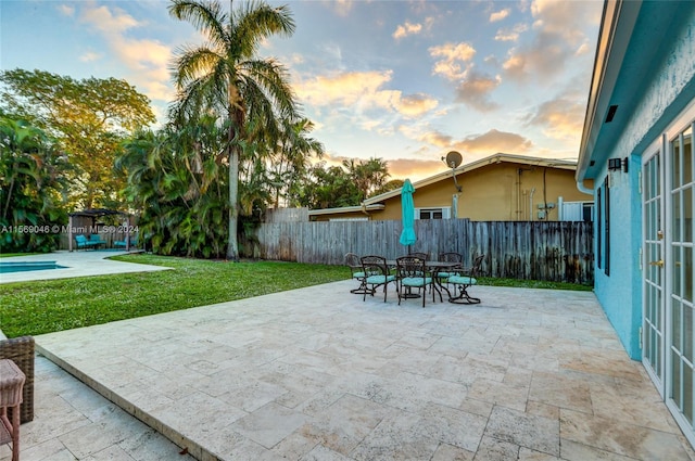 patio terrace at dusk with a pool and a lawn