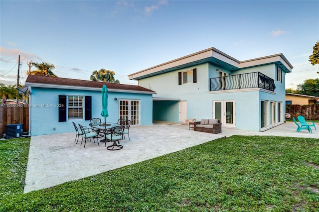 back of property with a balcony, a patio, central air condition unit, and a yard