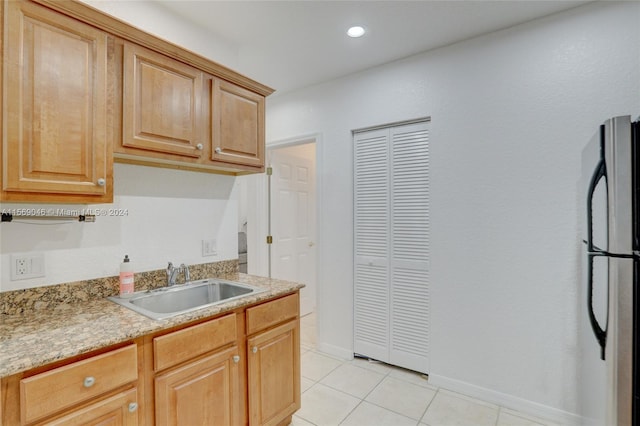 kitchen with light tile patterned flooring, stainless steel refrigerator, and sink