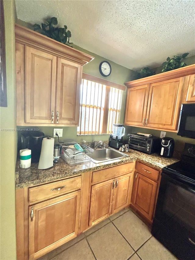 kitchen featuring stone countertops, a textured ceiling, sink, light tile flooring, and electric range