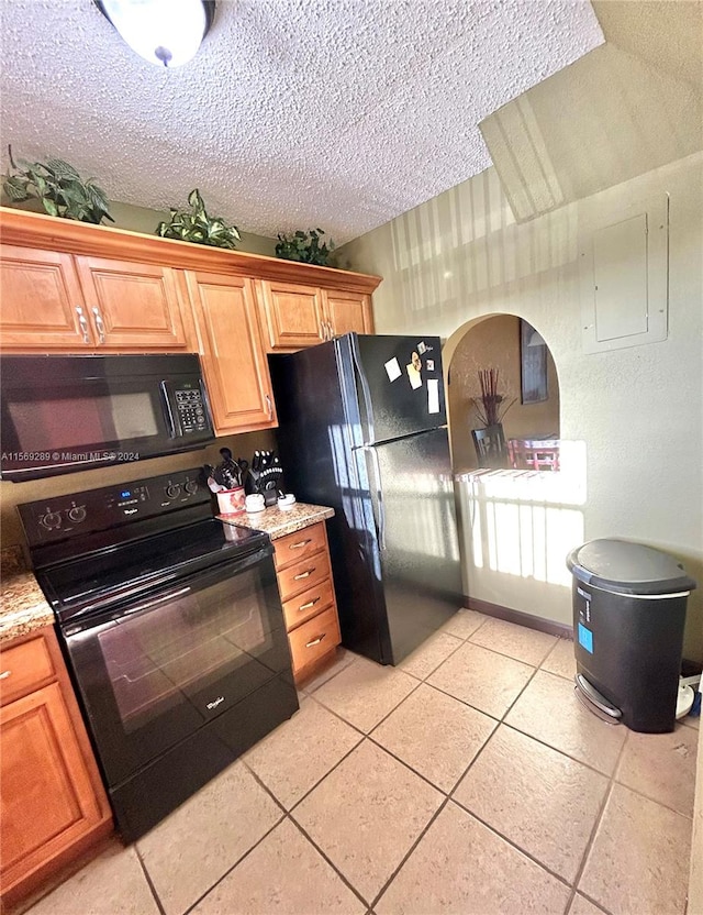 kitchen featuring black appliances, a textured ceiling, and light stone counters